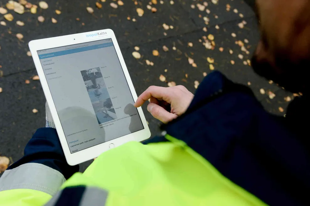 Icopal katto oyn kattokuntotarkastuksen tai kattikuntotutkimuksen raportti tabletilla kattotarkastajan kädessä katolla