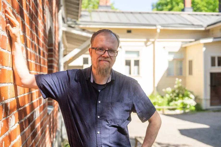 Kokoelmapäällikkö Teemu Ahola Museokeskus Vapriikista Amurin työläismuseokorttelin pihalla. Taustalla kolmiorimakattoinen vanha puutalo.